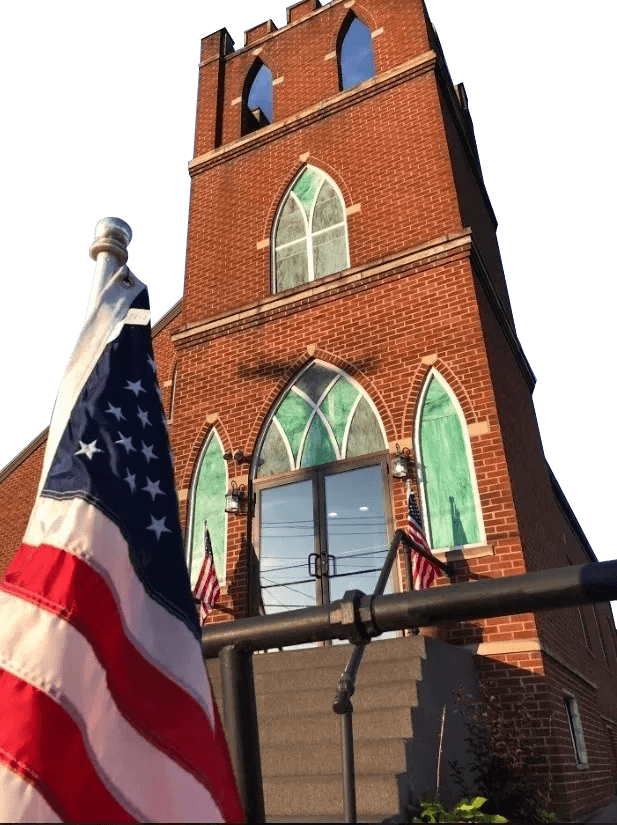 American flag waving in front of a historic brick church